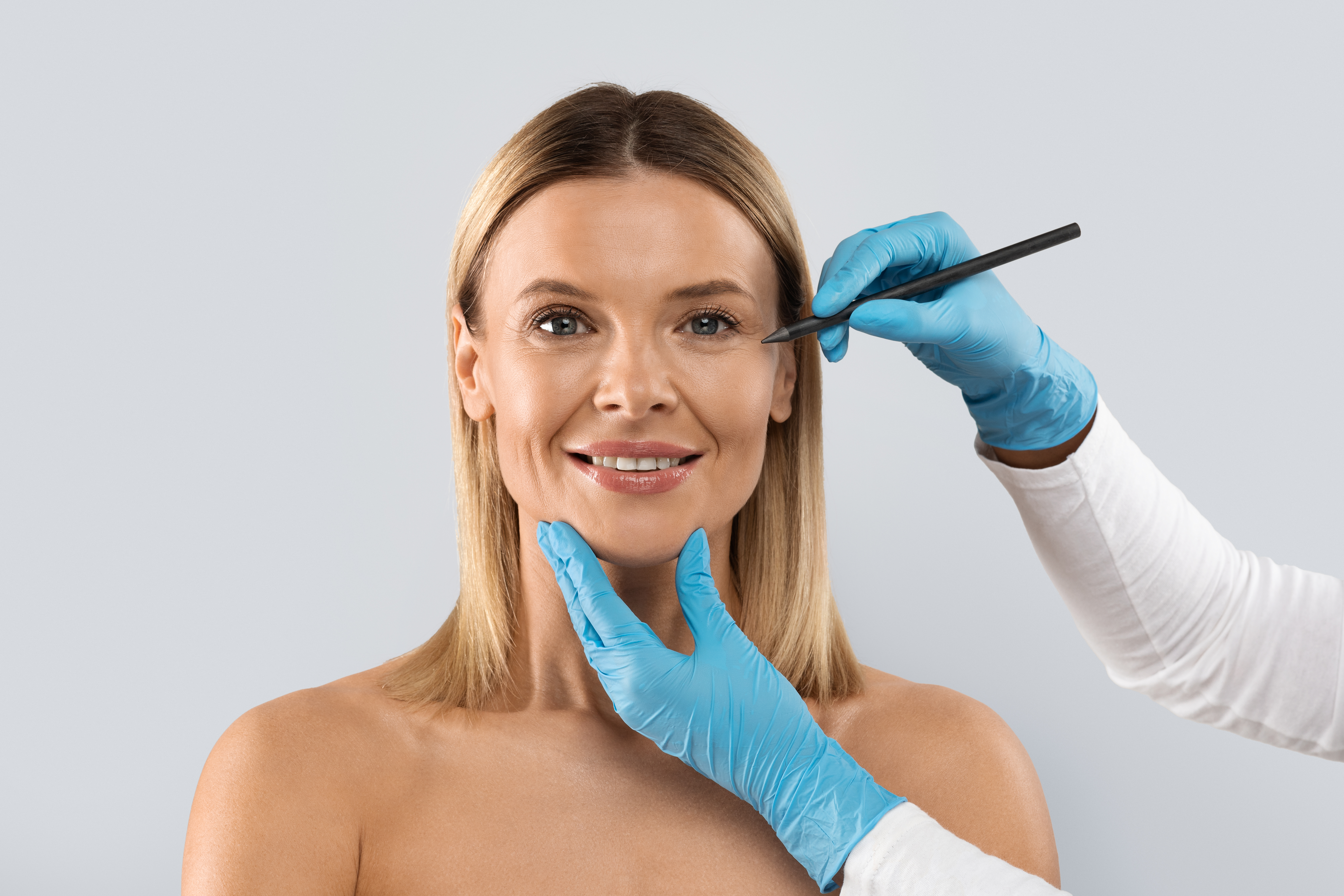 Plastic surgeon drawing lines on middle aged woman face